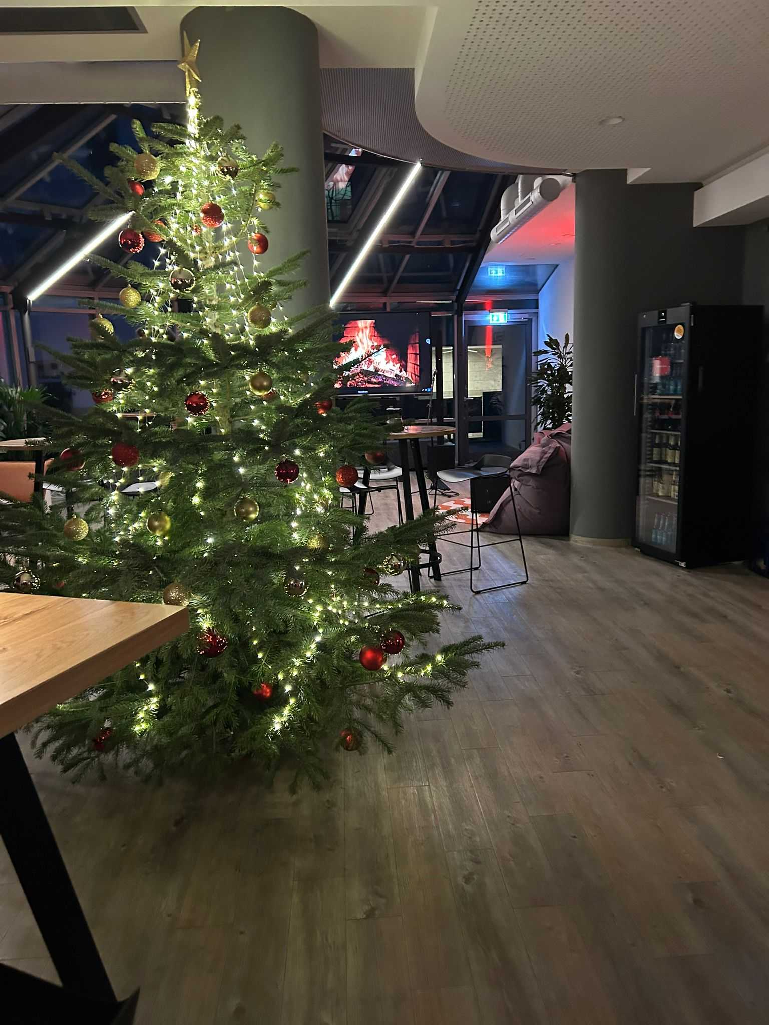 Festlich geschmückter Weihnachtsbaum mit Lichterketten und rot-goldenen Kugeln im Veranstaltungsraum