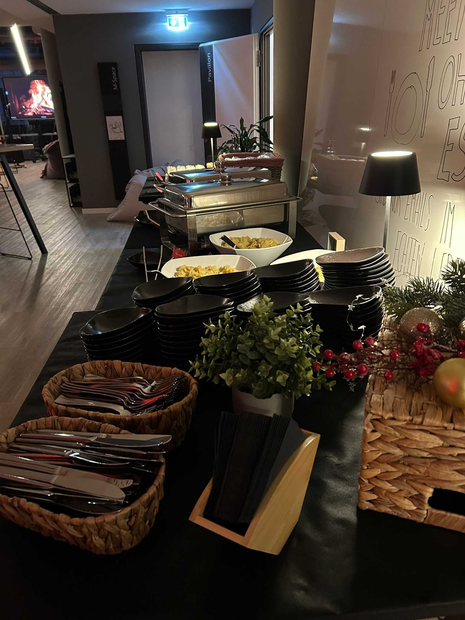 Festlich dekoriertes Buffet mit Chafing-Dishes, gestapelten Schälchen und Körben voller Besteck